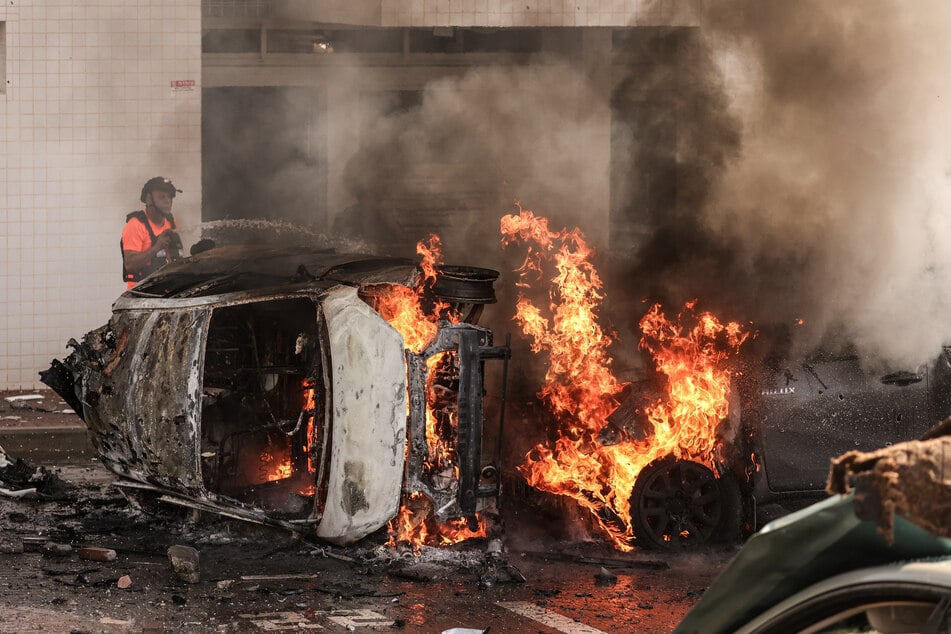Nach einem Raketenangriff aus dem Gazastreifen versuchen Menschen in Ashkelon, das Feuer auf Autos zu löschen.