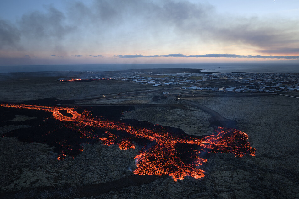 Lava explosions and billowing smoke are seen near residential buildings in the southwestern Icelandic town of Grindavik after a volcanic eruption on January 14, 2024.