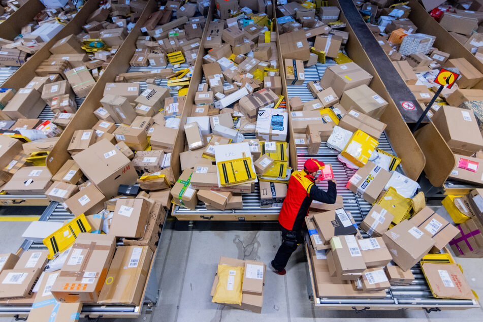 Ein Paketzusteller sortiert und räumt in einer Zustellbasis von Deutsche Post DHL Pakete in ein Zustellfahrzeug. Im diesjährigen Weihnachtsgeschäft rechnet die Deutsche Post DHL wieder mit Paketmassen - und vielen Krankmeldungen.