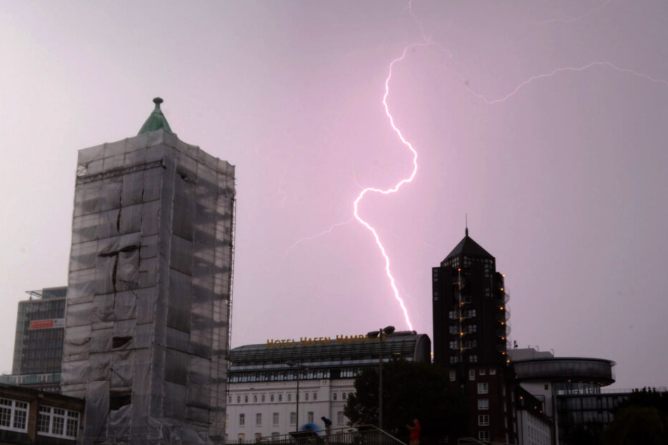 Ein Blitz zuckt während eines Gewitters bei den Landungsbrücken in Hamburg am Himmel.