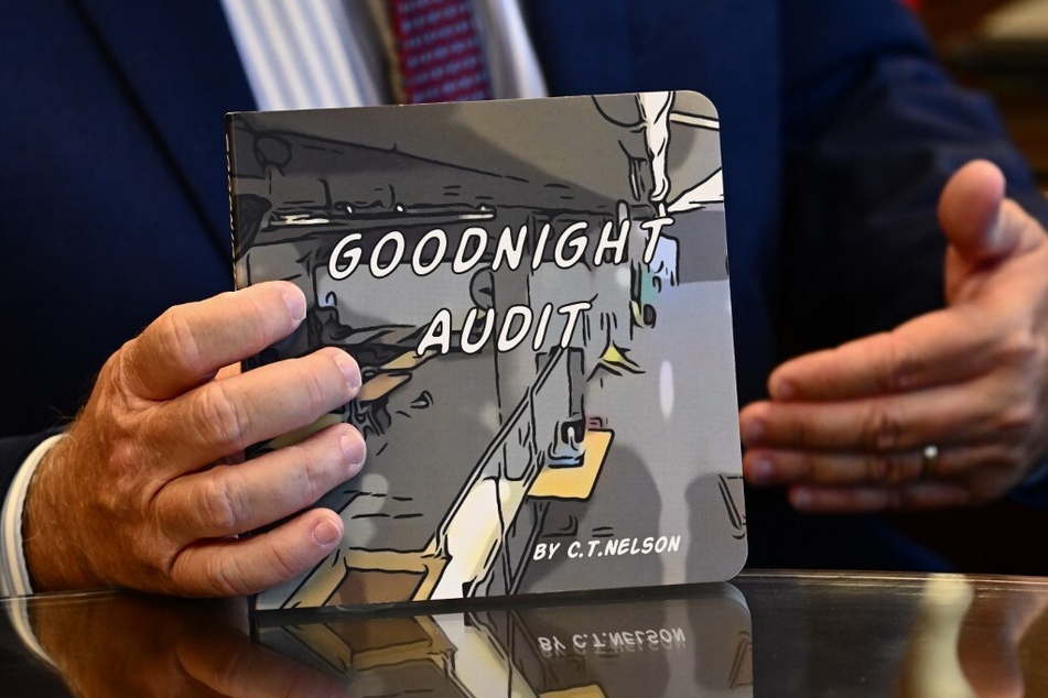 Bill Gates holds a copy of the Goodnight Audit children’s book by Trevor Nelson.