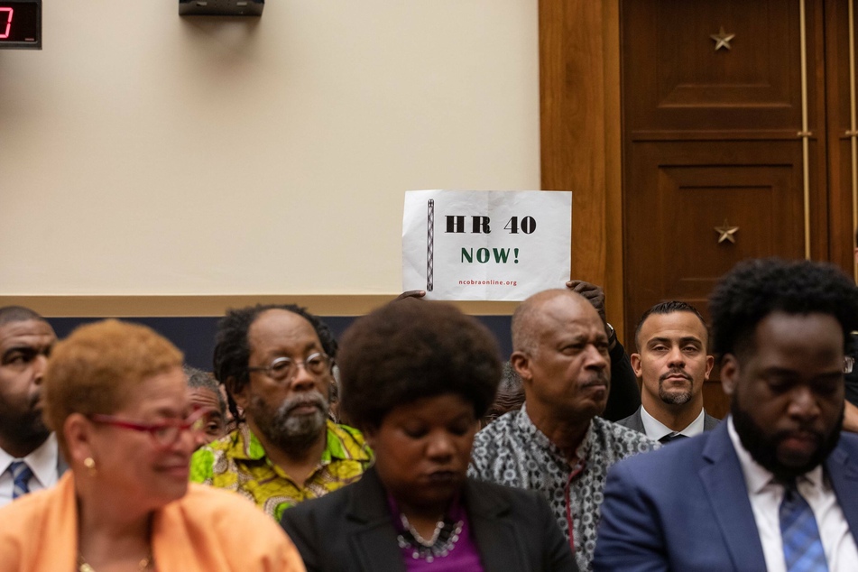 An attendee holds up a sign in support of HR 40 during a hearing before the House Judiciary Subcommittee on the Constitution, Civil Rights, and Civil Liberties in June 2019.