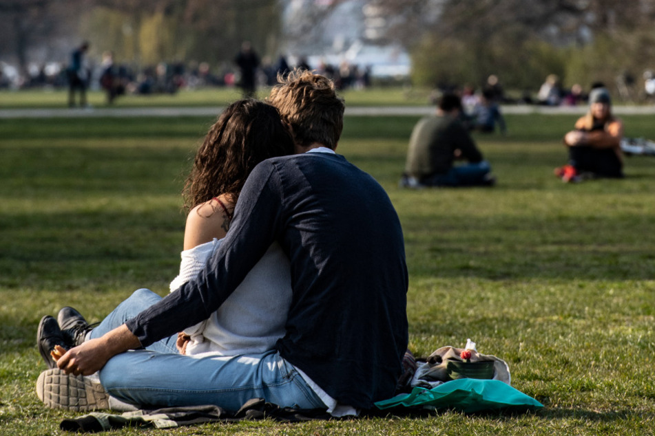 Ein Pärchen sitzt verbotener Weise im Treptower Park auf der Wiese zusammen.