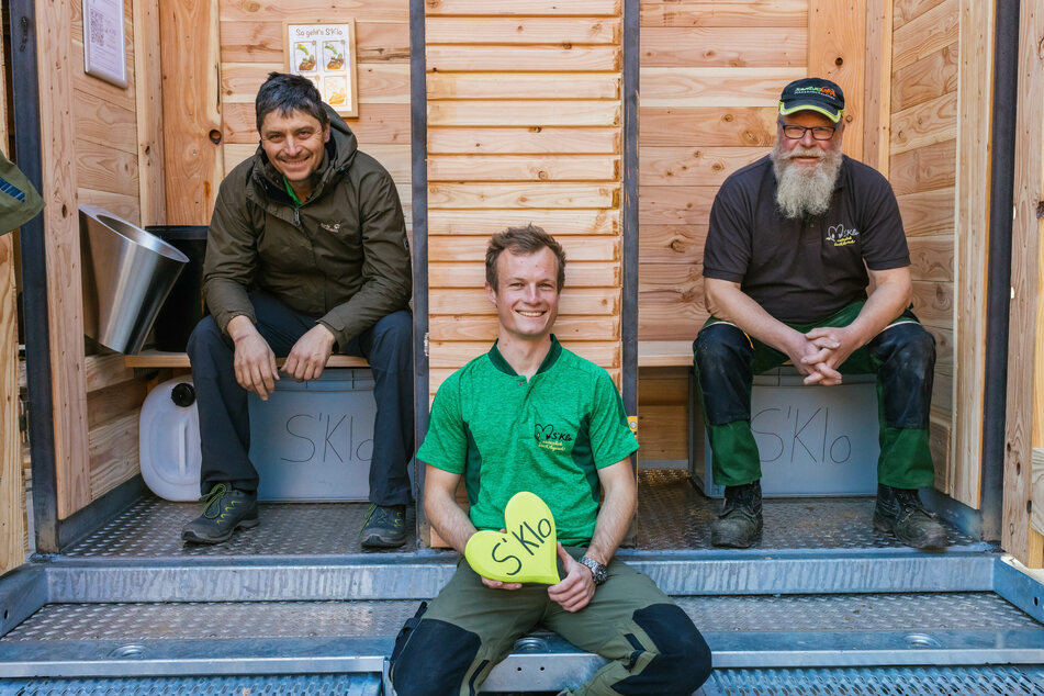 Fridolin Einwald (l-r), sein Geschäftspartner Michael Heizmann und ihr Helfer Ralf Grünsteidl sitzen in einem WC-Anhänger, den die drei gerade konstruieren.
