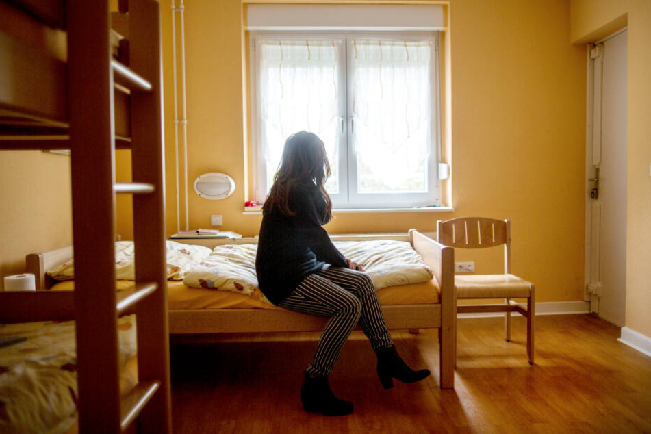 Eine Frau sitzt im Frauenhaus auf einem Bett.