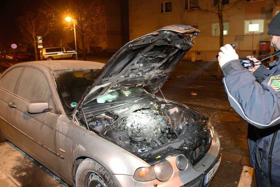 Ein Polizist macht Fotos von dem ausgebrannten Motorraum.