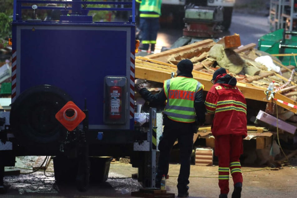Hilfskräfte stehen bei der Suche nach Verschütteten vor Trümmern eines explodierten Wohnhauses.