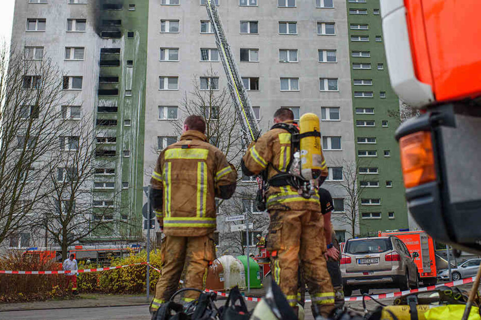 Feuerwehrkräfte stehen vor dem Hochhaus.