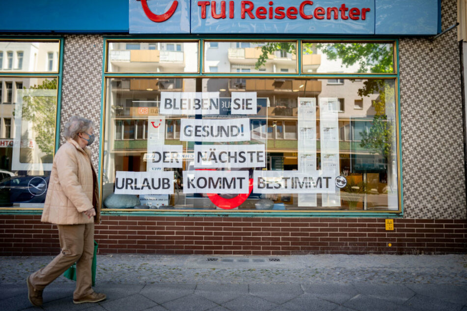 Eine Passantin mit Mund-Nasenschutz geht an einem Reisebüro vorbei.