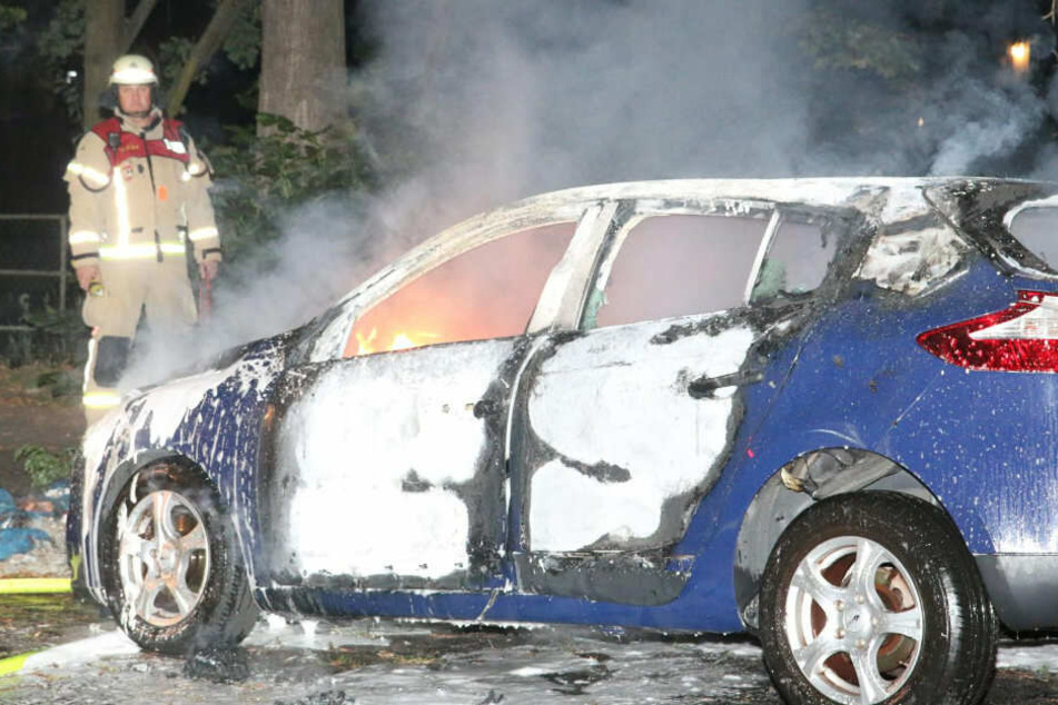 Ein Feuerwehrmann betrachtet ein ausgebranntes Auto am Kiehlufer in Berlin-Neukölln.