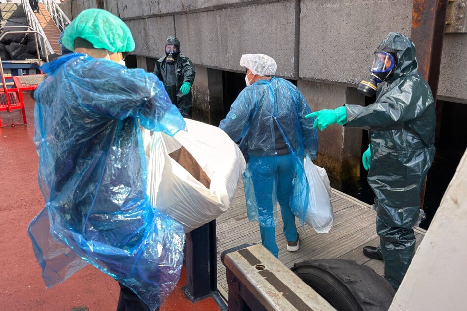 Ein Beamter der Guardia Civil in Schutzanzug und mit Gasmaske überwacht die Situation, während Personen vom Hantavirus befallenen Kreuzfahrtschiff MV Hondius im Hafen von Granadilla auf Teneriffa ausgeschifft werden.