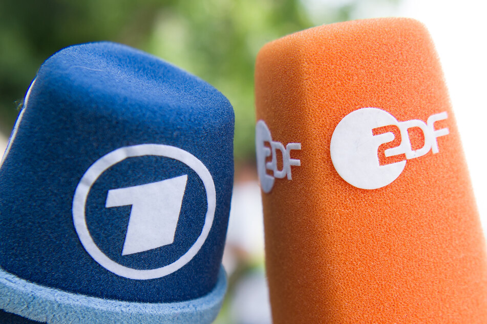 Fernsehmikrofone mit den Logos von ARD und ZDF werden nebeneinander gehalten.