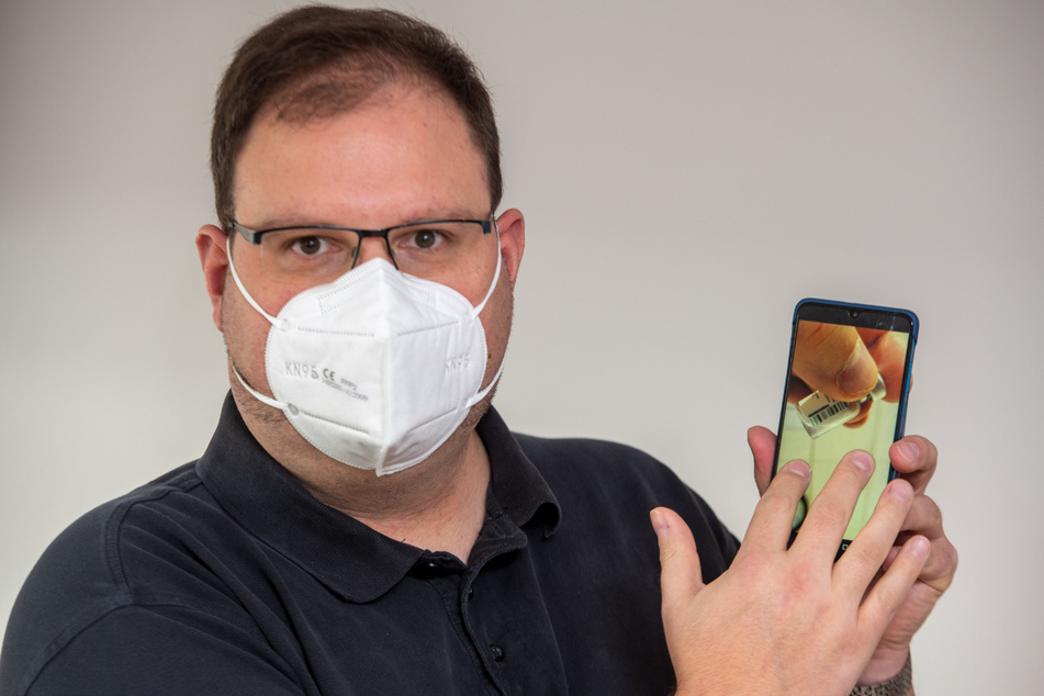Allgemeinarzt Christian Kröner zeigt auf seinem Mobiltelefon das Foto einer Ampulle mit Impfstoffresten.