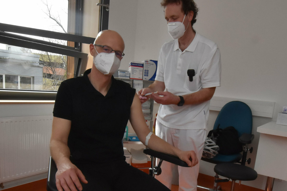 Prof. Gunnar Folprecht (r.), Leiter des Fachbereichs Onkologie des Uniklinikums Dresden, impft Peer Schmidt. Der Leukämiepatient wird seit 2016 nach erfolgreicher Stammzelltransplantation am Dresdner Uniklinikum ambulant nachbetreut.