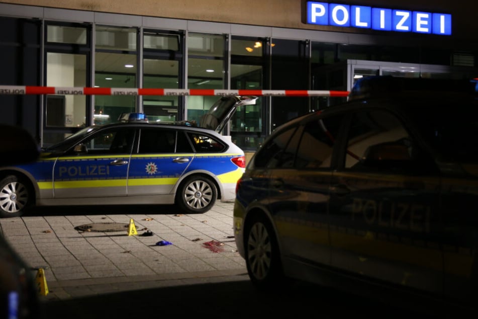 Ein Tatort vor einer Polizeistation ist mit einem Absperrband für Ermittlungsarbeiten abgegrenzt.