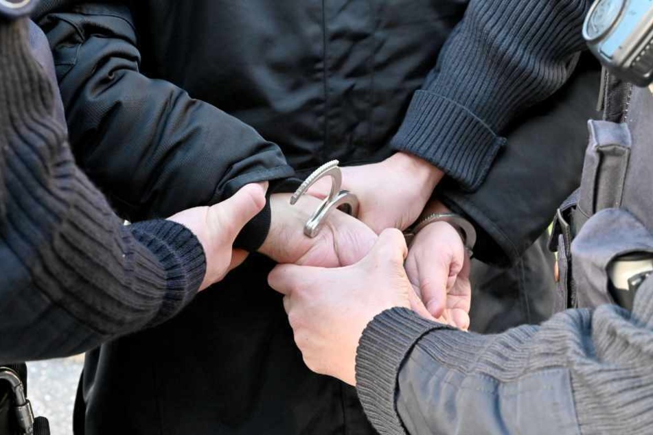 Polizisten legen einem Tatverdächtigen Handschellen an.