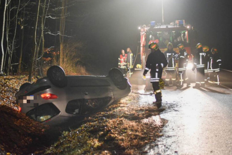 Der Peugeot liegt auf dem Dach im Straßengraben. Einsatzkräfte sind vor Ort.