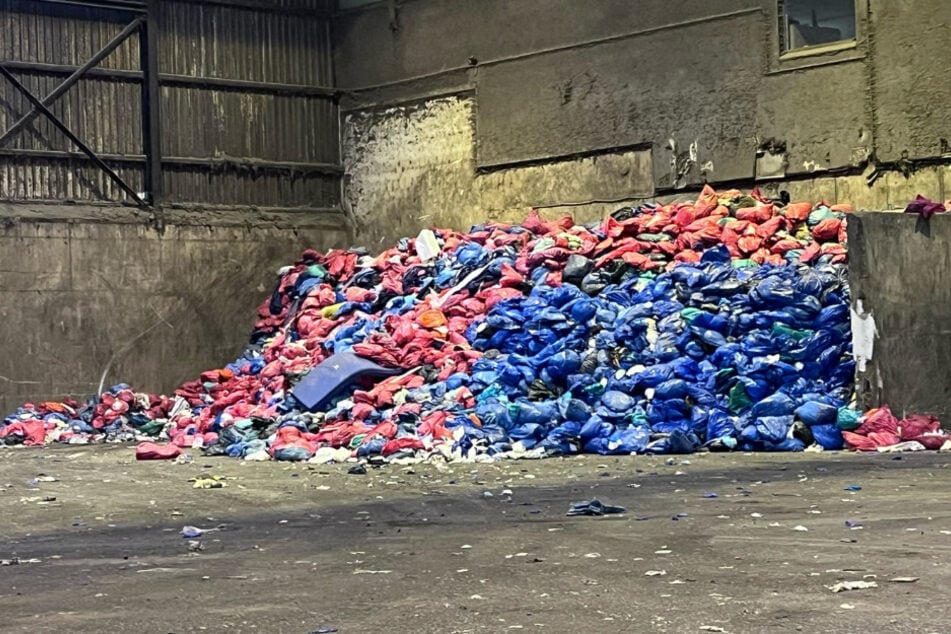 Rote und blaue Säcke mit Klinikmüll lagern aufgeschichtet im Müllbunker des AWVC.