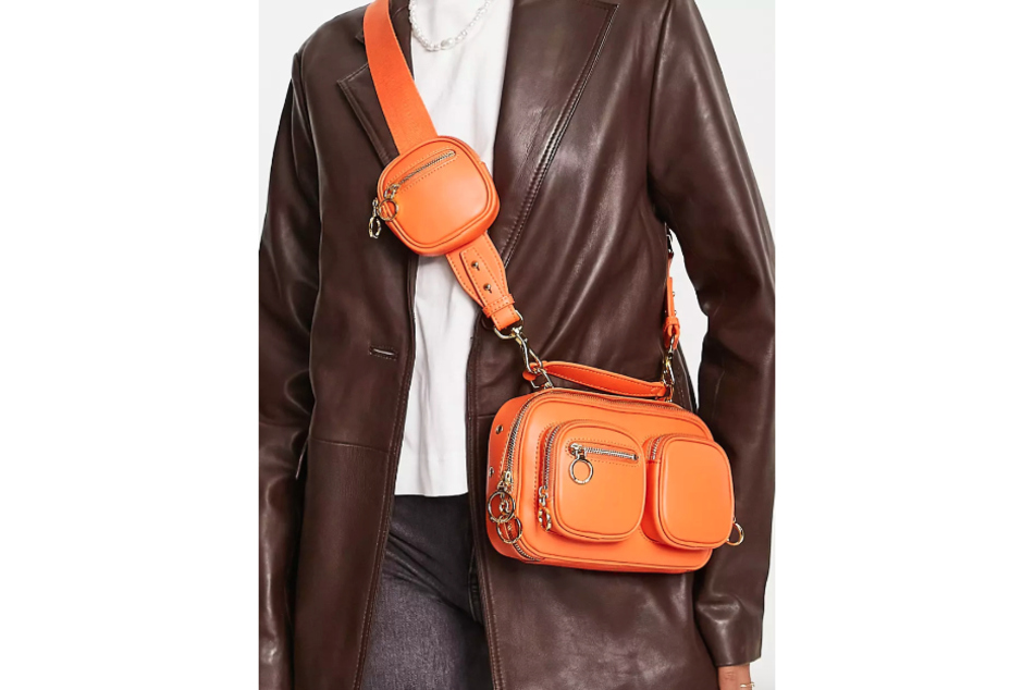 Die orangefarbene Tasche im Stil einer Kameratasche verleiht dem Look etwas Lässiges.