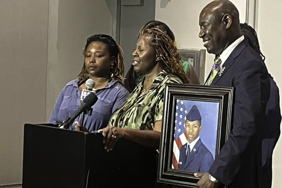 Meka Fortson (c.), the mother of Senior Airman Roger Fortson, speaks in May 2024 about the police killing of her son as attorney Ben Crump (r.) looks on.