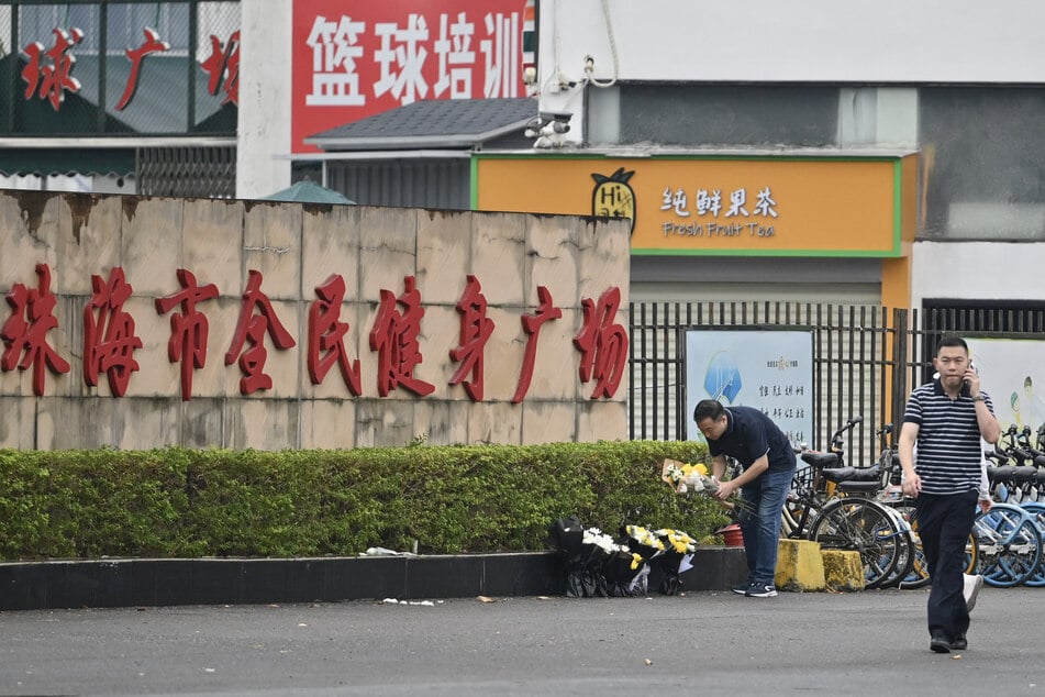 Workers remove flowers from a makeshift memorial outside the Zhuhai Sports Center in Zhuhai in south China's Guangdong province on November 13, 2024, two days after 35 people were killed when a man drove a car into a crowd in one of the country's deadliest mass-casualty events in years.