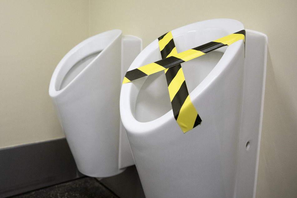 Eines der Urinale ist mit Absperrband abgeklebt, um einen Mindestabstand bei der Benutzung zu gewährleisten.