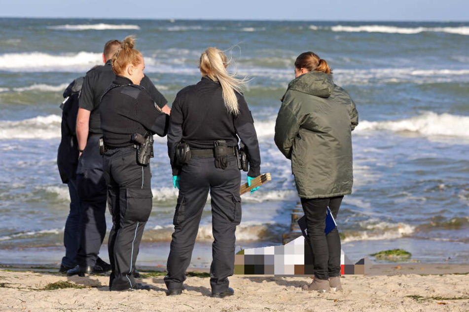 Polizisten untersuchen die Leiche am Ostseestrand.