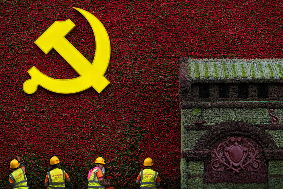 Peking: Arbeiter bringen Blumen an einer Dekoration mit dem Logo der Kommunistischen Partei an.