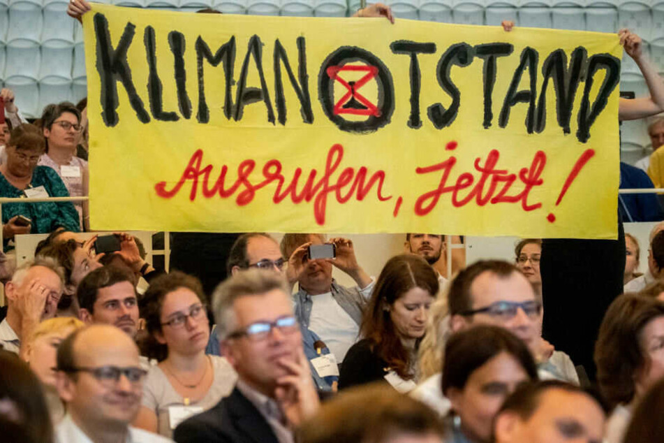 Besucher halten während einer Rede von Kanzlerin Angela Merkel in Berlin ein Transporten hoch.