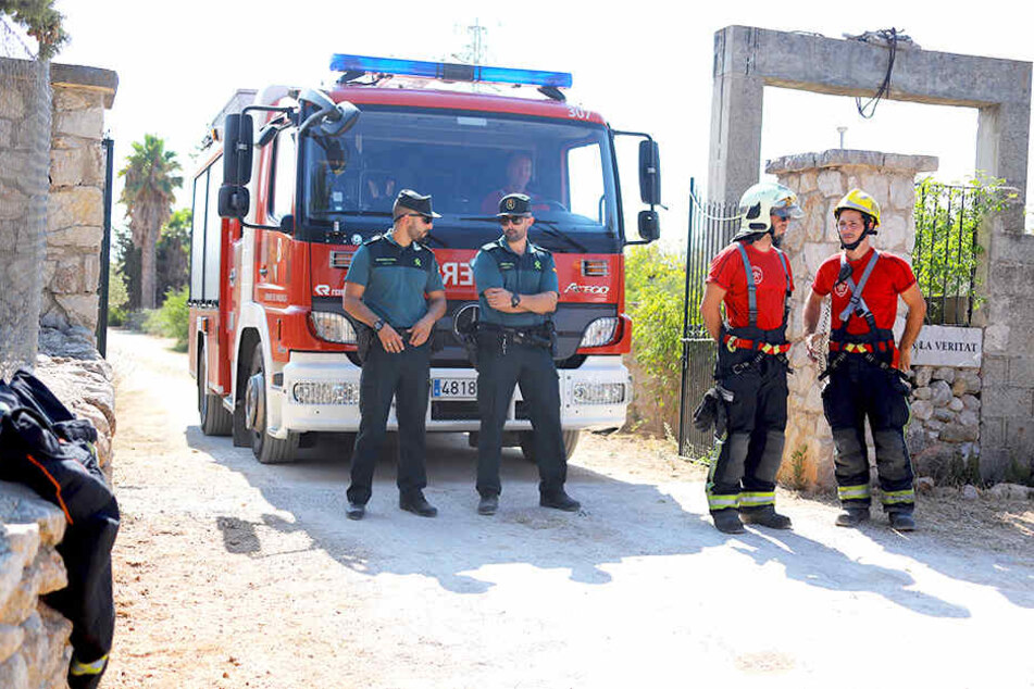Mitglieder der Polizeieinheit "Guardia Civil" (l.) und der Feuerwehr stehen nach einer Kollision zwischen einem Flugzeug und einem Hubschrauber in der Nähe der Absturzstelle.