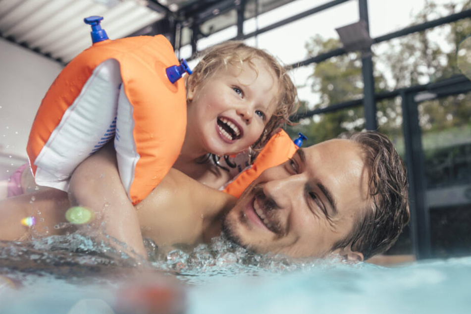 Auf Papas Rücken erobert diese kleine Wassernixe das Schwimmbad. Wetten, dass die Kleine in wenigen Jahren schon die "Seepferdchen"-Prüfung erfolgreich ablegt?