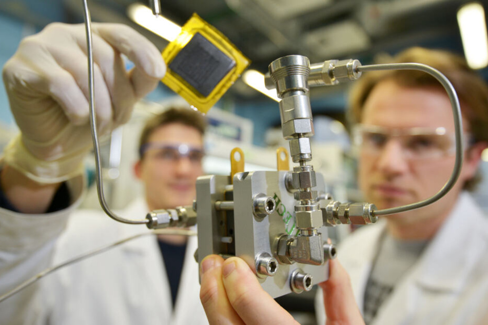 Die TU-Chemiker Leonard Rößner (28, l.) und Benjamin Hentschel (28) zeigen eine Brennstoffzelle und ihr Kernstück, die "Membran-Elektroden-Einheit."