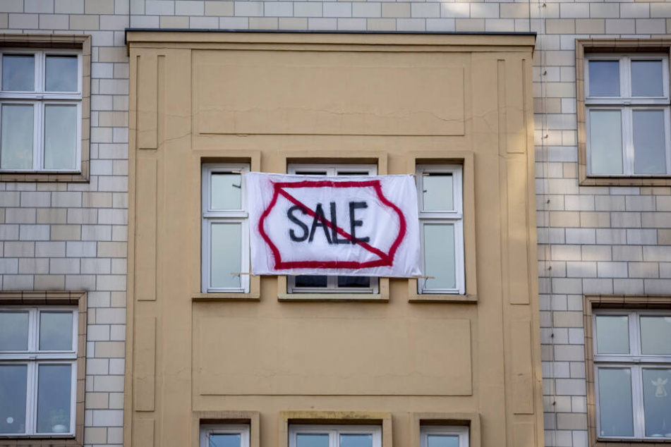 Ein Plakat gegen den Verkauf von Mietwohnungen an die Deutsche Wohnen SE mit dem durchgestrichenen Wort "Sale" hängt an einer Gebäudefassade in der Karl-Marx-Allee.