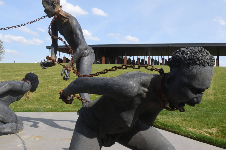 A sculpture commemorating the legacy of enslavement stands before a memorial honoring more than 4,000 victims of US racial lynchings in Montgomery, Alabama.