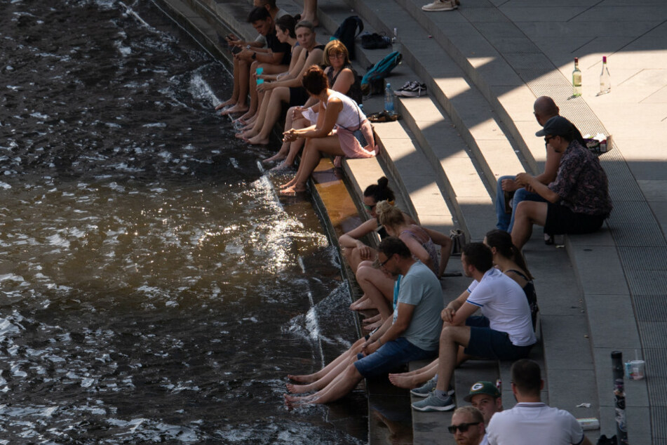 Menschen sitzen am Ufer der Spree im Regierungsviertel und genießen das gute Wetter.