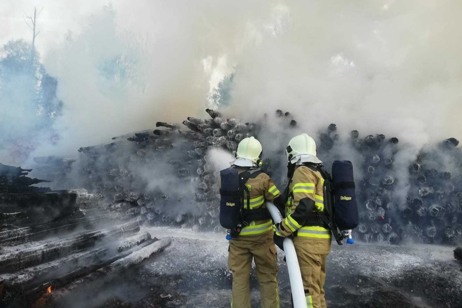 Die Feuerwehr ist seit Stunden im Einsatz, kann die betroffenen Holzstapel aktuell jedoch nur kontrolliert abbrennen lassen.