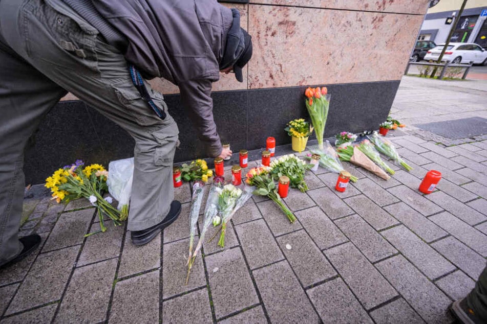 Ein Mann legt unmittelbar in der Nähe des Tatorts Blumen ab.