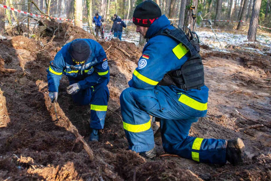 Zwie Helfer des Technischen Hilfswerks (THW) untersuchen den Boden in einem Waldstück, in dem die Polizei nach der Leiche der vermissten Katrin Konert gegraben hat.