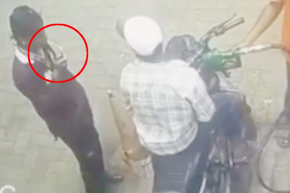 Ein Mann raucht im indischen Raipur direkt neben einem Motorrad, welches gerade aufgetankt wird.