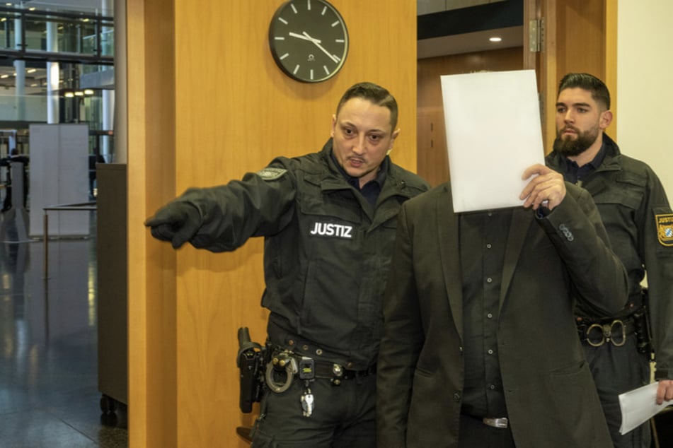 Im Strafjustizzentrum bringen zwei Justizwachtmeister den angeklagten Vater (M.) in den Saal.