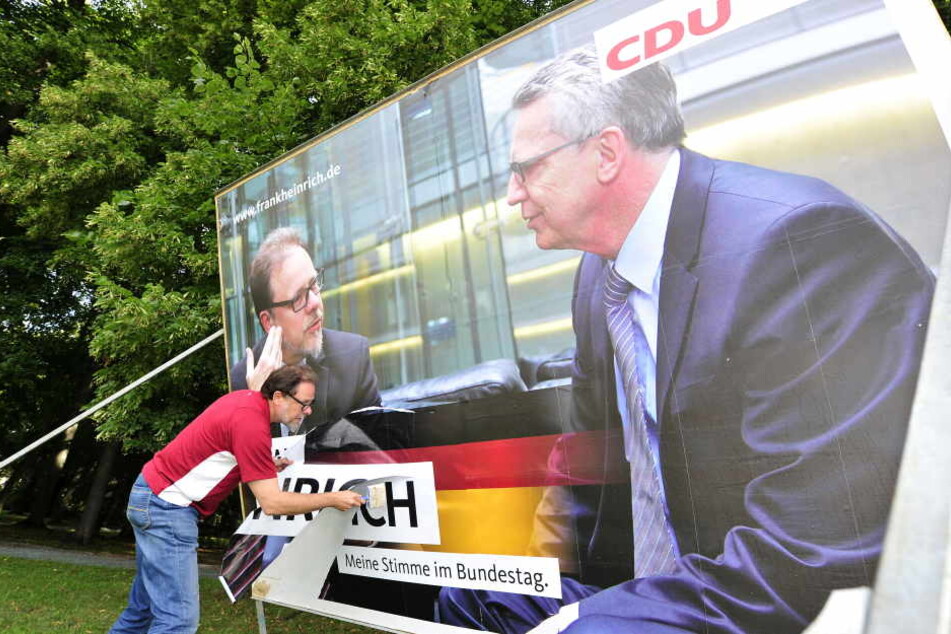 Frank Heinrich (CDU) versuchtdas Plakat an der Hartmannstrasse notdürftig zu reparieren