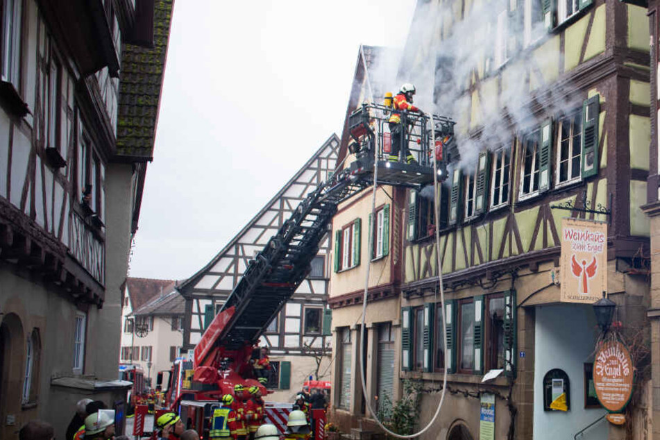 Feuerwehrleute stehen vor dem brennenden Fachwerkhaus in Neudenau.
