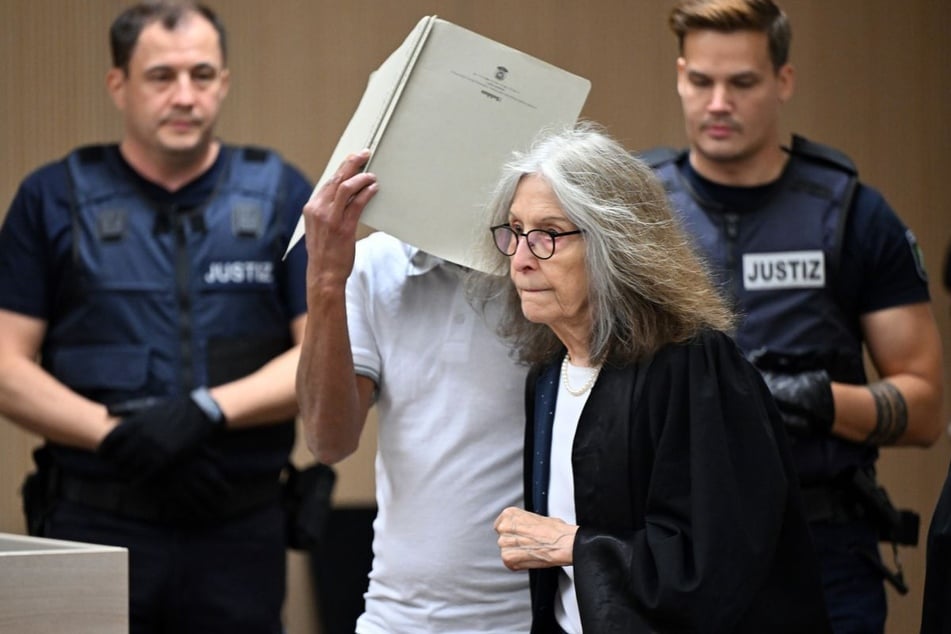 Der Angeklagte (M.) wird von seiner Verteidigerin Silvia Oster (2.v.r.) in den Gerichtssaal geführt und verdeckt dabei sein Gesicht.