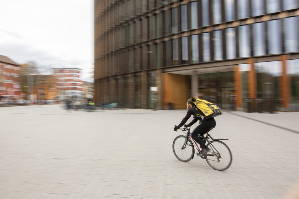 Ein Fahrradkurier fährt vor dem Freiburger Rathaus im Stühlinger entlang.