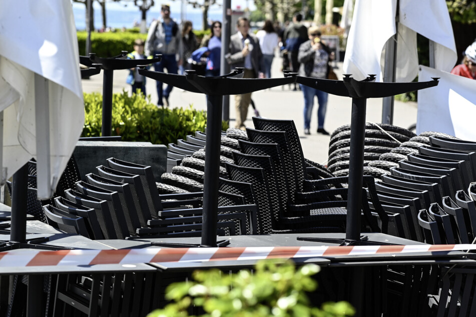 Stühle und Tische stehen aufgereiht an der Uferpromenade, während im Hintergrund Passanten laufen. Der Inzidenzwert ist noch zu hoch, sodass die Außengastronomie im Bodenseekreis nicht öffnen kann.