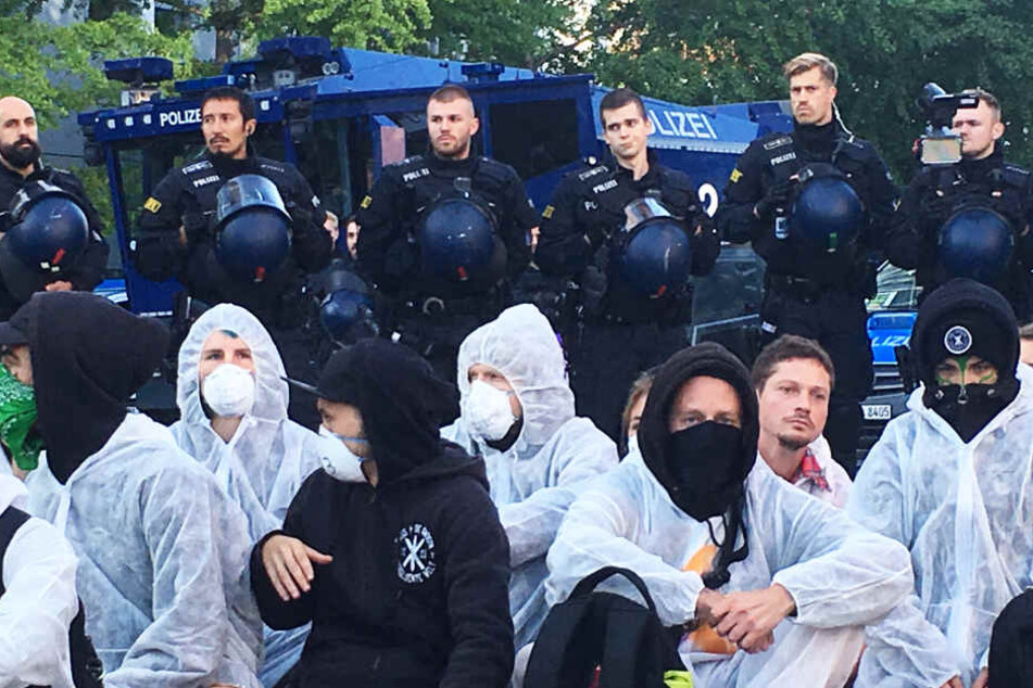 Das Foto zeigt Protestierende und Polizisten vor dem Eingang zum Frankfurter Messegelände. Im Hintergrund ist ein Wasserwerfer zu sehen.