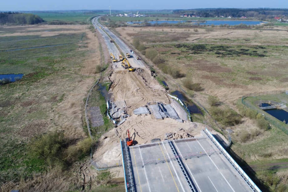 Bagger arbeiten am Rückbau des Straßendammes an dem zerstörten Teilstück der Autobahn A20.