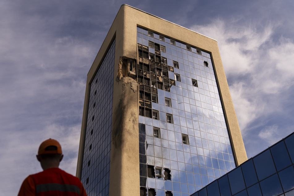 Ein Wartungsarbeiter begutachtet nach russischen Drohnenangriffen ein beschädigtes Regierungsgebäude.