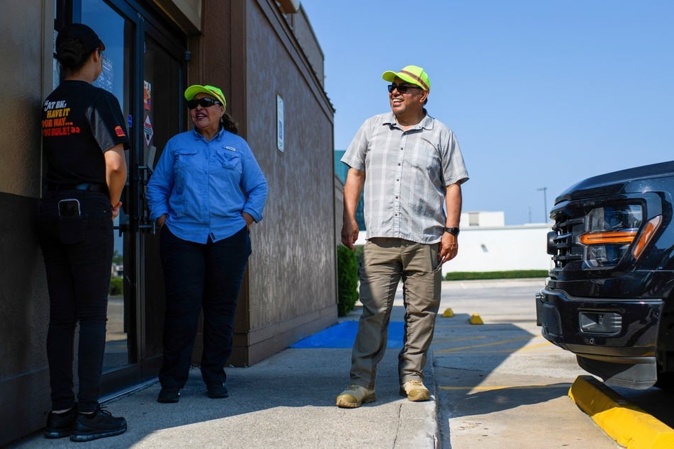 Martina Grifaldo (c.) and Francisco Mendoza (r.) talk with a fast food restaurant worker while tracking ICE operations in Houston, Texas, on September 17, 2025.