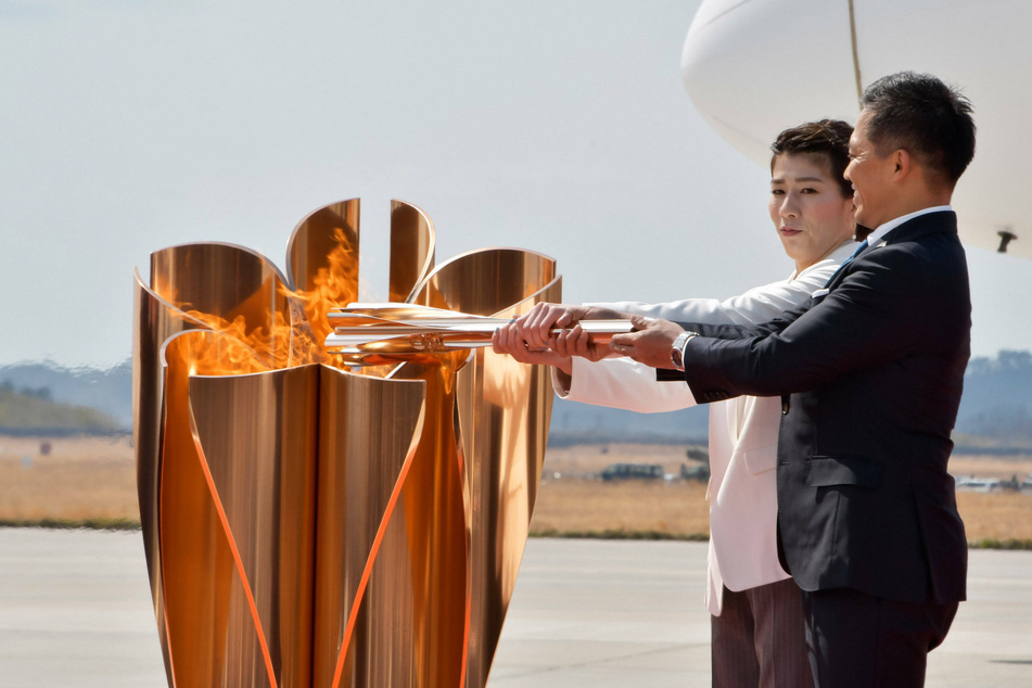 Three-time Olympic gold medalists Tadahiro Nomura (front) and Saori Yoshida light the torch during the Olympic Flame Arrival Ceremony.